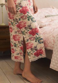 Lilleline hommikumantel punaste ja roheliste mustritega kreemjas taustas, külgsest lõhiku ja pitsäärisega põhjaga.