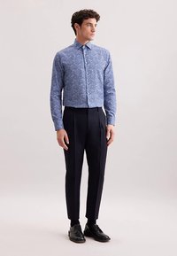 Blauw bloemenoverhemd met knopen en lange mouwen, gecombineerd met marineblauwe, op maat gemaakte broek en zwarte leren schoenen, getoond op een mannelijk model.