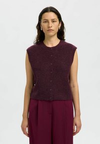 Gilet senza maniche di un profondo borgogna, lavorato a maglia, con scollatura rotonda, bottoni frontali e una texture morbida, abbinato a pantaloni a vita alta coordinati.