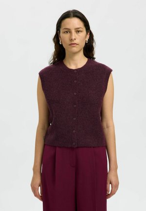 Gilet sans manches en maille bordeaux profond avec un col rond, des boutons à l'avant et une texture douce, associé à un pantalon taille haute assorti.