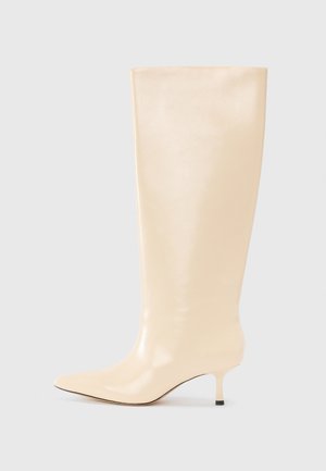 Knee-high beige leather boot with a sleek, smooth finish, pointed toe, and a low, slender heel. Features minimalistic design and no visible accents.