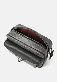 Borsa a mano rettangolare in pelle nera testurizzata con una parte superiore a motivo grigio. Presenta una cerniera argentata, un interno rosso e una chiusura con gancio metallico.