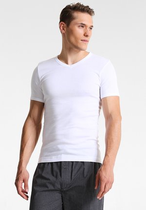 White short-sleeve V-neck t-shirt, made of smooth cotton fabric, fitted design, with no visible patterns or logos. Worn with checkered shorts.