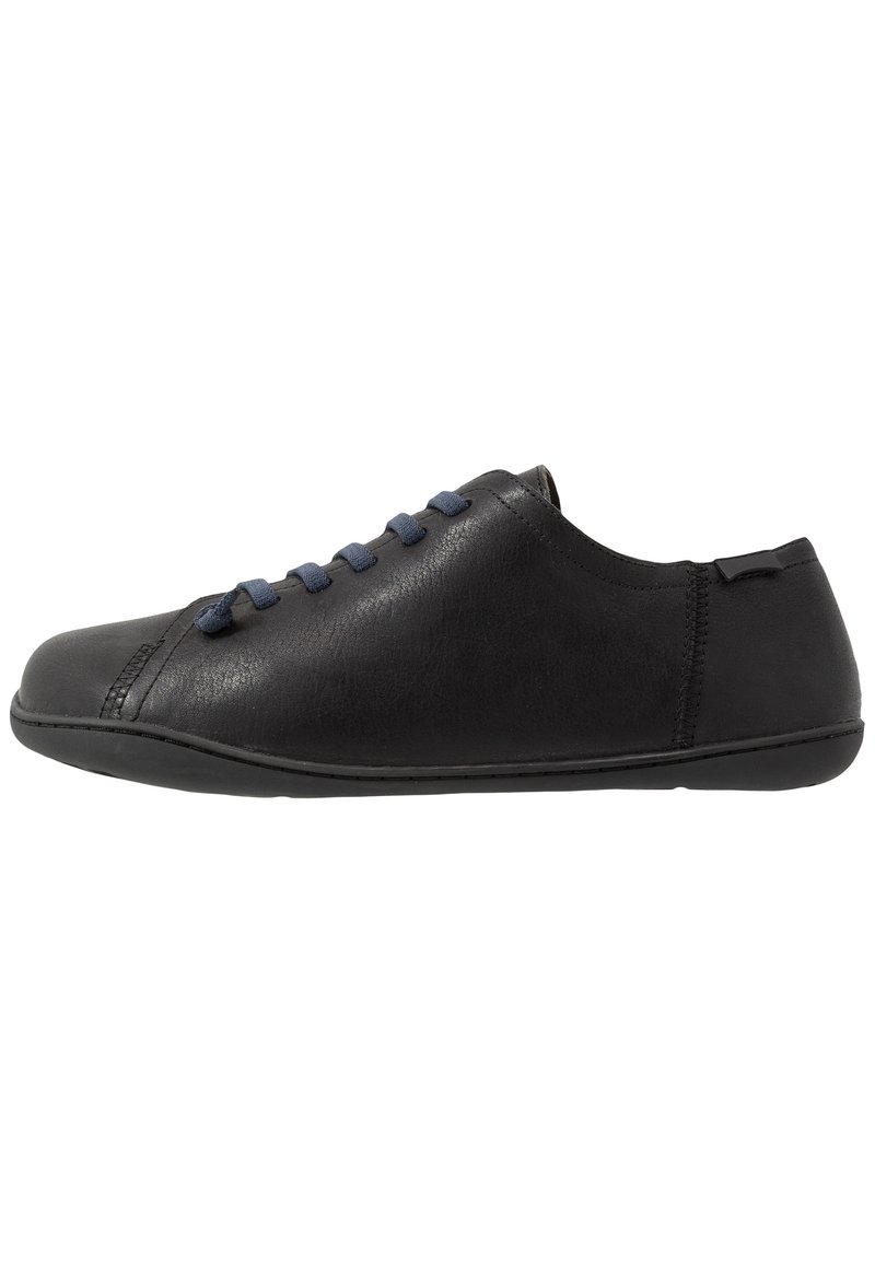 Zapato de cuero negro con un perfil bajo, punta redonda y cordones azul marino. Presenta una textura suave y detalles de costura a lo largo de los lados.