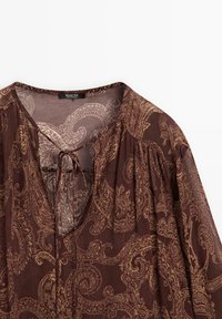 Blusa marrone a maniche lunghe con motivo paisley, tessuto leggero, scollatura a V con dettaglio a fiocco e maniche arricciate per un effetto texture.