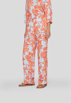 Helle blaue Baumwollhose mit großem orangen Blumendruck, lockere Passform, elastischer Bund mit Zugkordel. Kombiniert mit braunen flachen Sandalen.