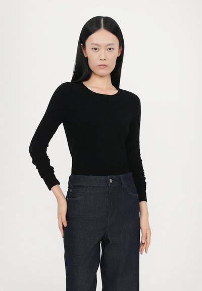 Black long-sleeve top with a textured pattern, paired with dark blue denim jeans. The outfit features a round neckline and slim fit.