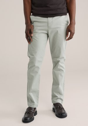 Lichtgroene katoenen broek met een slanke pasvorm, zijzakken en een gladde textuur, gecombineerd met zwarte instapschoenen.