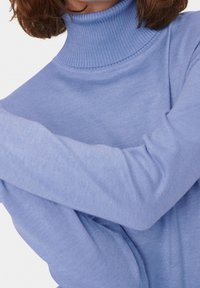 Hellblauer Rollkragenpullover aus geripptem Stoff, mit langen Ärmeln und hohem Kragen, im lockeren Schnitt gestaltet.