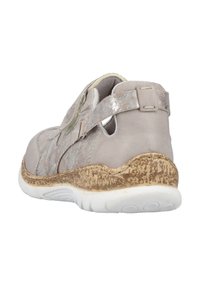 Beige Sneaker mit strukturiertem Design, ausgestattet mit einem Klettverschluss, gepolstertem Schuhsohle und hellen metallischen Akzenten. Abgerundete Ferse und unterstützende Struktur.