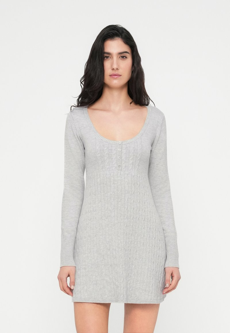 Γκρι πλεκτό φόρεμα με στρογγυλή λαιμόκοψη, μακριά μανίκια και ριμπ υφή, με σειρά κουμπιών στο μπροστινό μέρος. Ρυθμιζόμενη εφαρμογή.