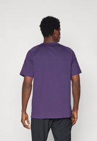 Paarse katoenen t-shirt met korte mouwen, ronde hals en een ontspannen pasvorm. Glad textuur met minimale naden en geen zichtbare patronen.