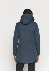 Veste imperméable bleu marine foncé avec capuche, manches longues, coupe jusqu'aux cuisses et texture lisse et matte.