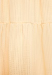 Tecido amarelo claro com riscas verticais e uma costura franzida, apresentando uma textura semi-translúcida e um caimento suave.