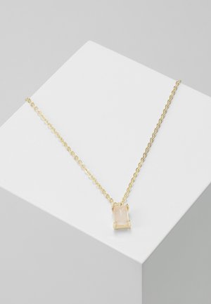 Collier délicat en chaîne d'or avec un pendentif rectangulaire en pierre précieuse rose pâle reposant sur une surface blanche inclinée.
