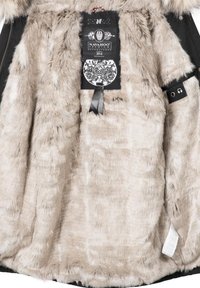 Doublure en fausse fourrure beige à l'intérieur d'un manteau avec une étiquette noire portant l'inscription "Navahoo Premium Established 2014" et des motifs décoratifs noirs et blancs.