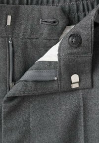 Pantalons texturés gris dotés d'une fermeture éclair, d'un bouton, d'accents métalliques et d'une taille élastique avec cordon de serrage. Intérieur avec doublure blanche.