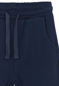 Navyblaue Jogginghosen aus weichem Stoff, mit einem elastischen Bund, dekorativem Kordelzug und seitlichen Taschen. Glatte Textur mit Nähdetails.