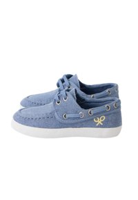 Zapatillas de lona azules con un acabado texturizado, suelas de goma blanca y logo de acento amarillo. Presentan cordones decorativos y ojales de metal.