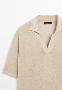 Beige short-sleeve sweater with a ribbed collar and v-neck design. Soft knit texture with subtle sheen and no visible patterns or accents.