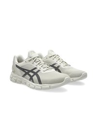 Scarpe da corsa leggere con una tomaia in mesh testurizzato e traspirante di colore bianco sporco, con accenti neri e una suola ammortizzata per il massimo comfort.