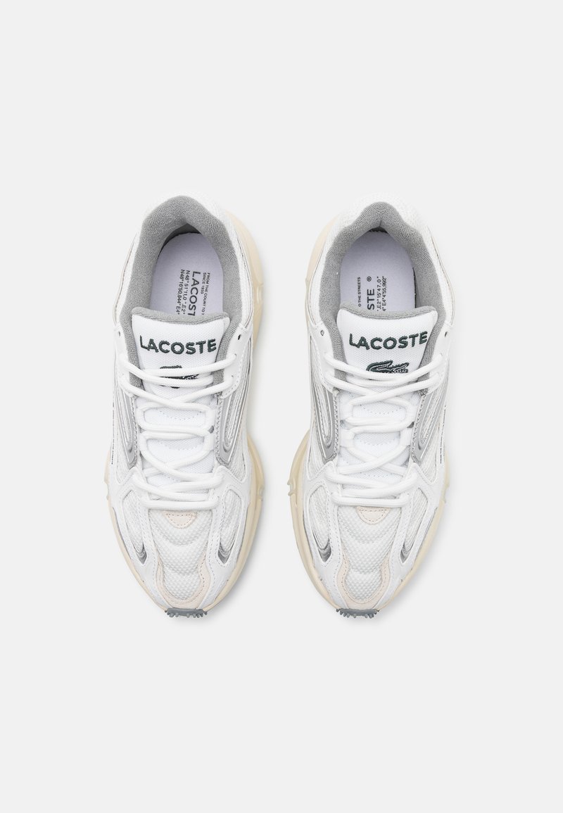 Baskets LACOSTE en mesh blanc et gris avec des superpositions texturées, des doublures grises et une semelle en caoutchouc couleur crème ; elles possèdent des lacets et un logo.
