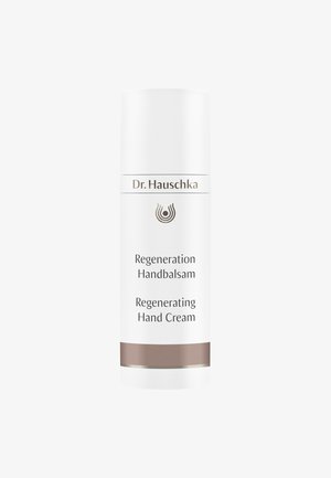 Tube cylindrique blanc avec un capuchon à rabat, présentant des accents bruns et un texte imprimé : "Dr. Hauschka Regeneration Handbalsam."