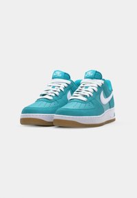 Tyrkysové semišové tenisky s bielymi detailmi, so zaoblenou špičkou, šnurovacím dizajnom a gumovou podrážkou. Logo Nike na boku.