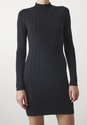 Robe noire en maille côtelée avec manches longues et col montant festonné. Silhouette ajustée, texture lisse et coupe à hauteur des genoux.