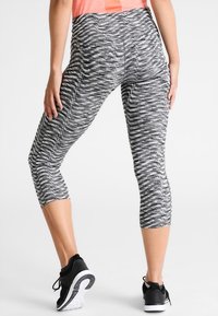 Šedé a černé marl legíny na sport s designem capri, zdobené texturovaným vzorem a vysokým pasem. V kombinaci s sportovními botami.