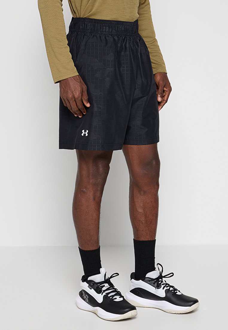 Shorts de sport noirs avec une taille élastique, présentant un motif géométrique. Associés à des chaussures de sport noir et blanc et des chaussettes noires.