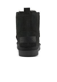 Černé semišové kotníkové boty s texturovaným povrchem, logem a měkkou kožešinovou podšívkou na vrchní části, navržené pro teplo a pohodlí.