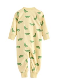 Gul bomullsoverall med gröna alligatormönster, långärmad, ribbstickade muddar och rund krage.