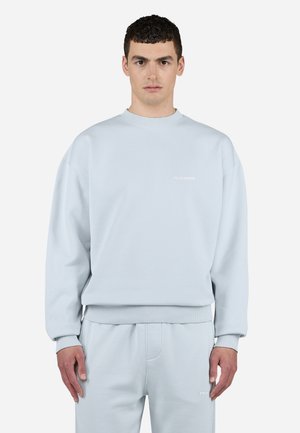 Light blue sweatshirt featuring a ribbed crew neck and cuffs, with a small, white "PEGADOR" logo on the chest, made of soft fabric.