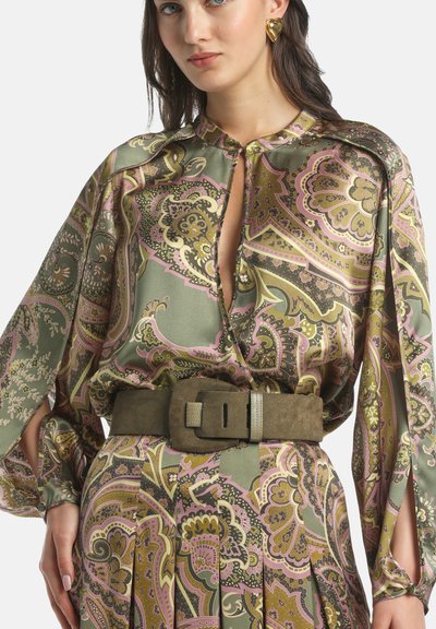 Zijden blouse met lange mouwen en een losse pasvorm, met een groen, roze en goud paisley patroon. Gecombineerd met een bruine suède riem met hardware accenten.