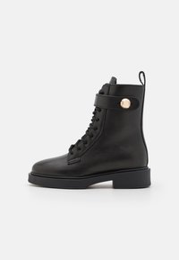 Stivale alla caviglia in pelle nera con punta tonda, design con lacci, fascetta laterale con bottoncino metallico e tacco a blocco. Texture liscia in tutto il modello.