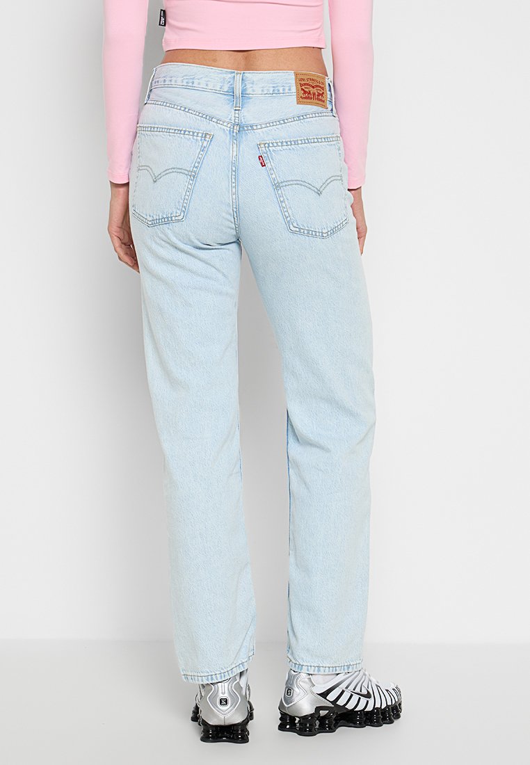 Jeans de mezclilla azul claro con un corte relajado, presentan una cintura alta, dos bolsillos traseros y una etiqueta de marca de cuero en la parte trasera de la cinturilla.