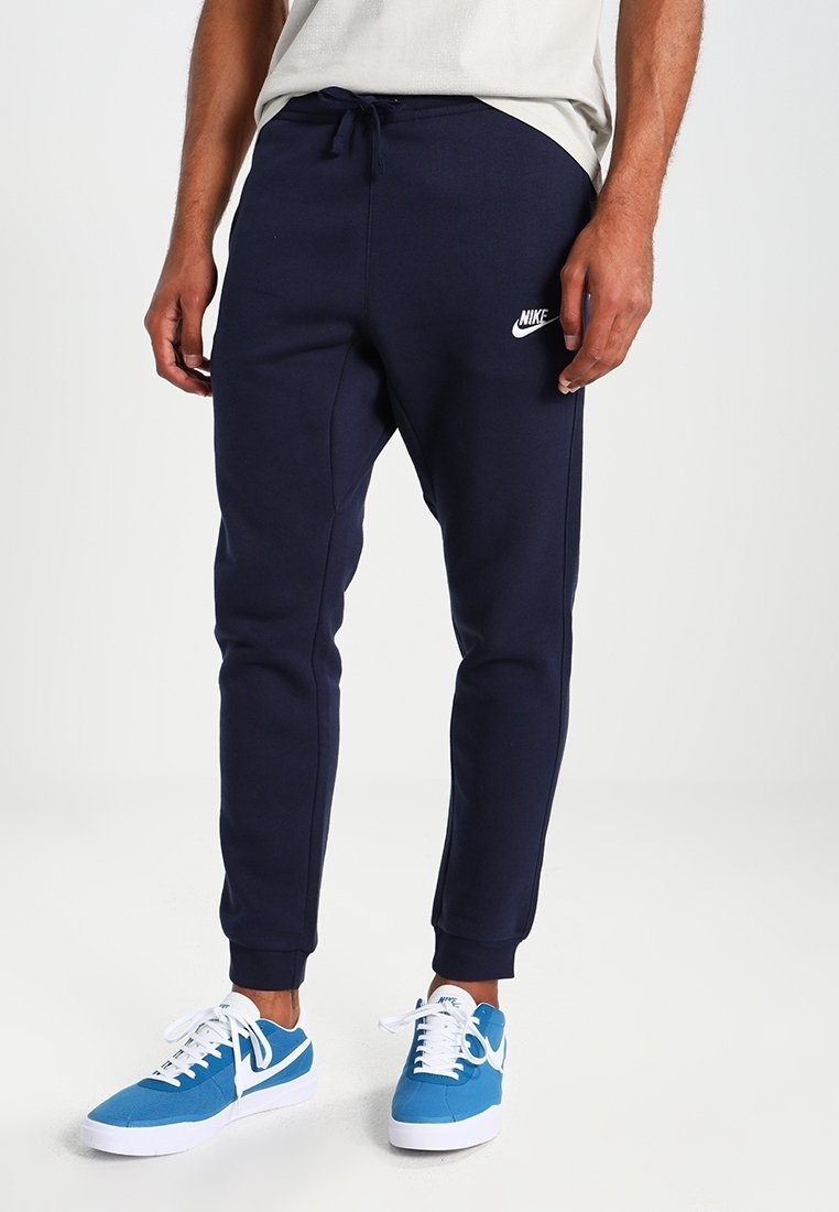 Pantalones deportivos de color azul marino hechos de un tejido suave, con una cintura elástica con cordón y un pequeño logo blanco de Nike a la altura de la rodilla.