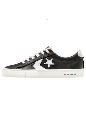 Czarny skórzany sneaker niskiego kroju z białym logo gwiazdy, białymi sznurowadłami i białą podeszwą z napisem "Pro Leather" po boku.