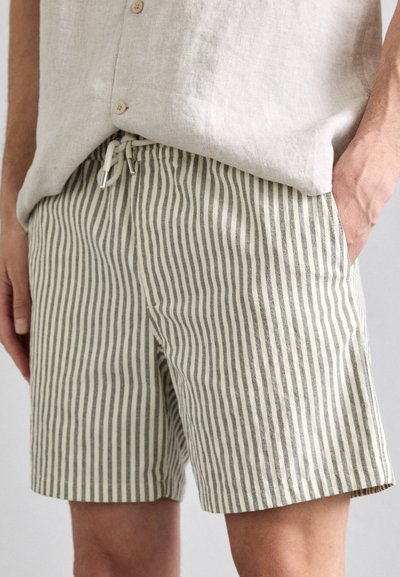 Pantaloni corti a righe in beige chiaro e verde oliva, caratterizzati da una vita con cordoncino e termini in metallo, realizzati in tessuto leggero.