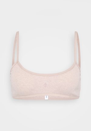 Light beige wireless bra made of soft fabric with thin adjustable straps and a small logo embroidered on the front. Textured finish.