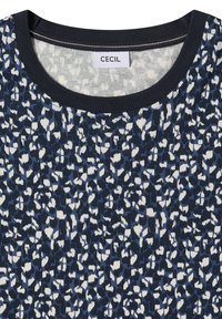 Haut bleu marine à col rond avec un motif léopard abstrait en noir, blanc et bleu, et une petite étiquette "CECIL" à l'intérieur du col.