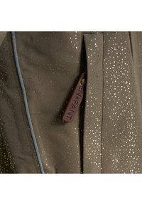 Bruine stof met een patroon van goudkleurige stippen; heeft een grijzige naad en een leren label met de opdruk "EN+FANT".