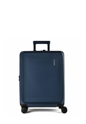Valise rigide bleue avec motifs texturés diagonaux, quatre roues noires, poignée rétractable et petit logo sur le panneau avant.