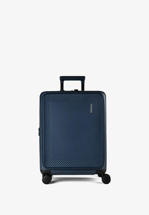 Valise rigide bleue avec motifs texturés diagonaux, quatre roues noires, poignée rétractable et petit logo sur le panneau avant.