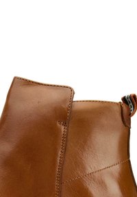 Brown leather ankle boot featuring a smooth texture, rounded toe, raised seam detail, and a loop for easy pulling.