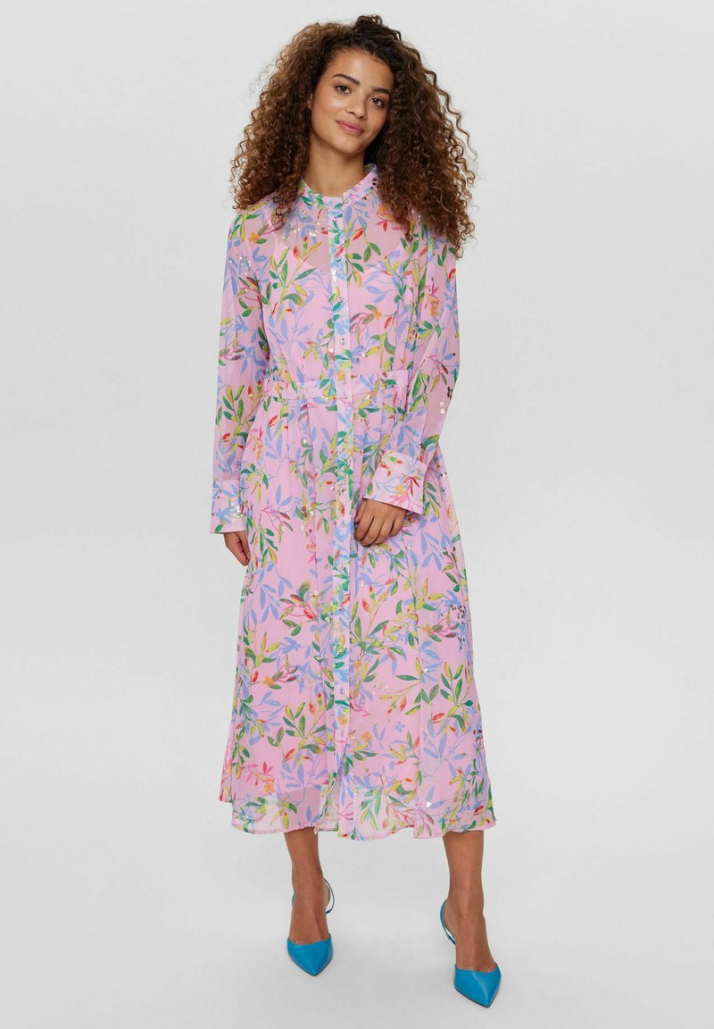 Robe longue fleurie rose avec des boutons bleus, présentant des motifs de feuilles vertes et rouges. Manches longues et ourlet légèrement évasé.