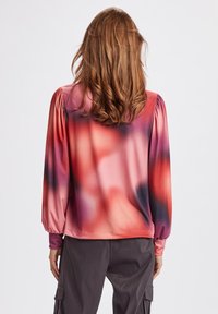 Blus med lång ärm och en gradientdesign i nyanser av rosa och lila. Slät tyg med skräddarsydda axelsömmar och åtsittande manschetter.