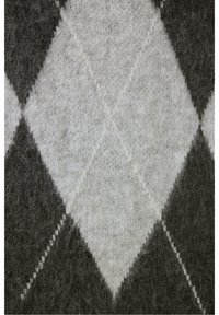 Gros plan d’un tissu tricoté avec un motif losanges argyle gris et noir présentant des lignes diagonales croisées.