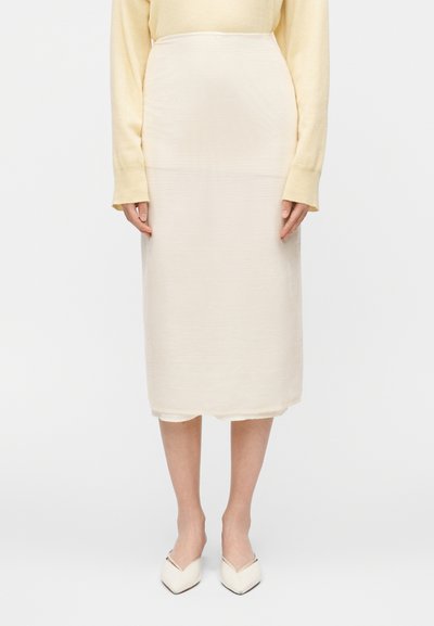 Jupe crème longueur genou en tissu texturé. Caractérisée par une taille mi-haute, une coupe droite et un détail subtil à l'ourlet.